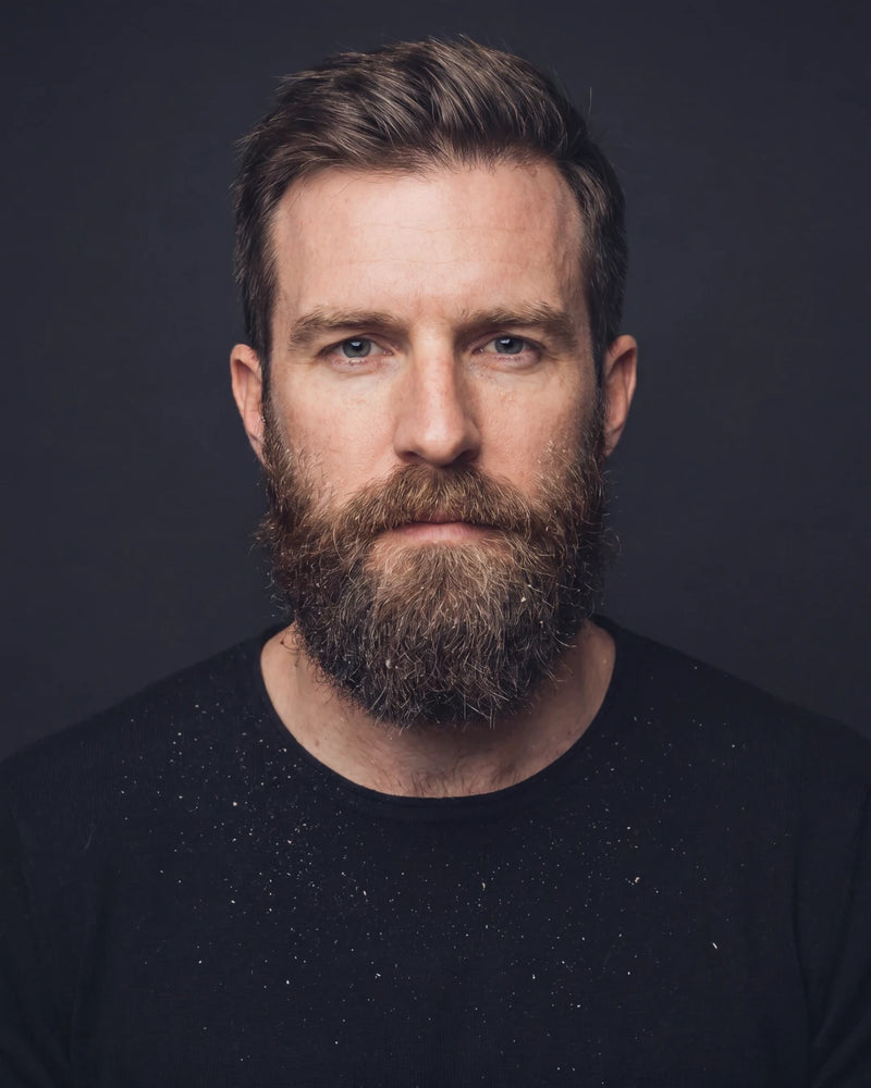 Man with a beard wearing a black shirt against a dark background