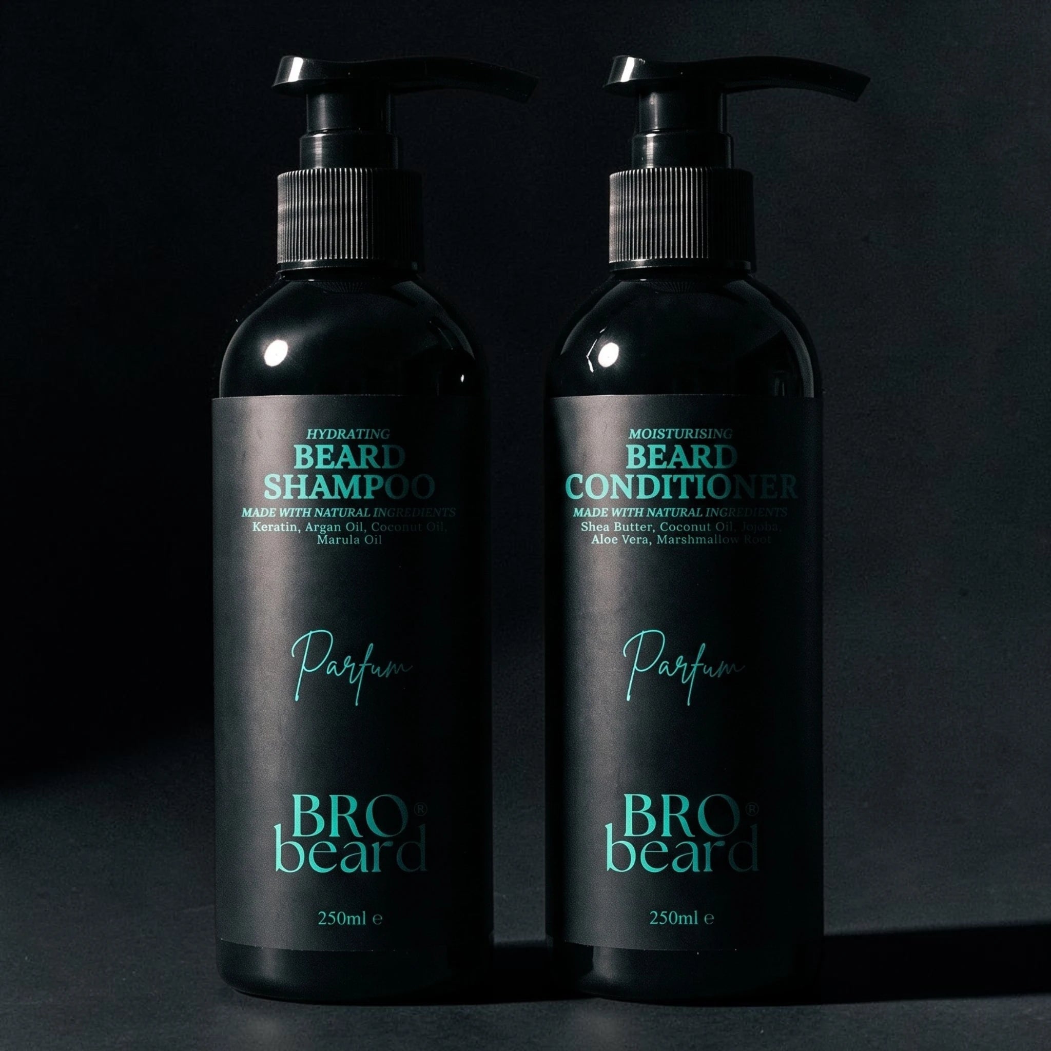 Two black pump bottles of beard care products, labeled 'Beard Shampoo' and 'Beard Conditioner' with teal text, standing side by side on a dark surface against a dark background.